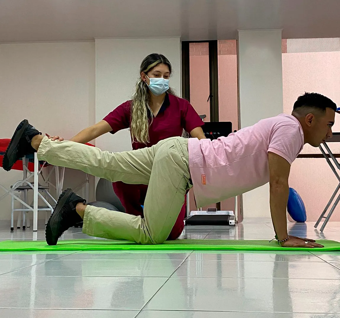 Valentina corrigiendo la postura de un paciente durante un ejercicio en colchoneta