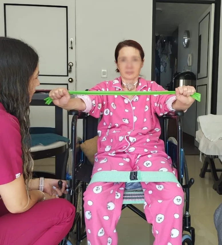 Valentina haciendo terapia con banda elástica a una paciente en su casa